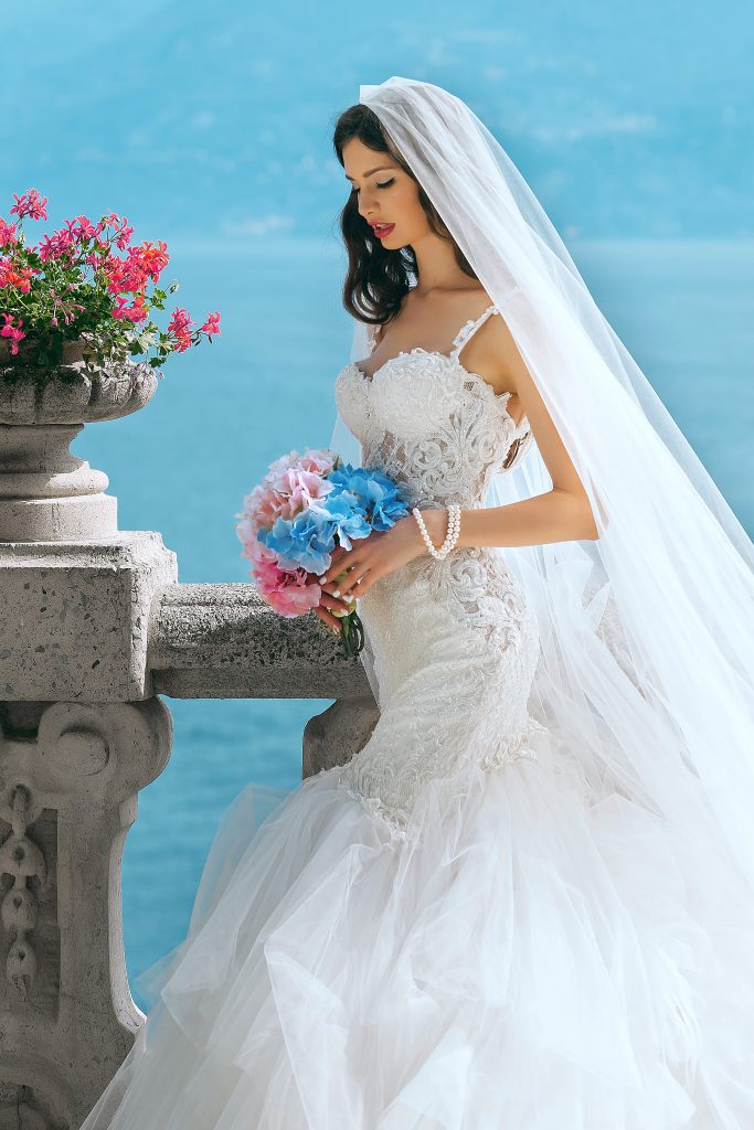 Woman in a wedding dress holding a bouquet of red and blue flowers